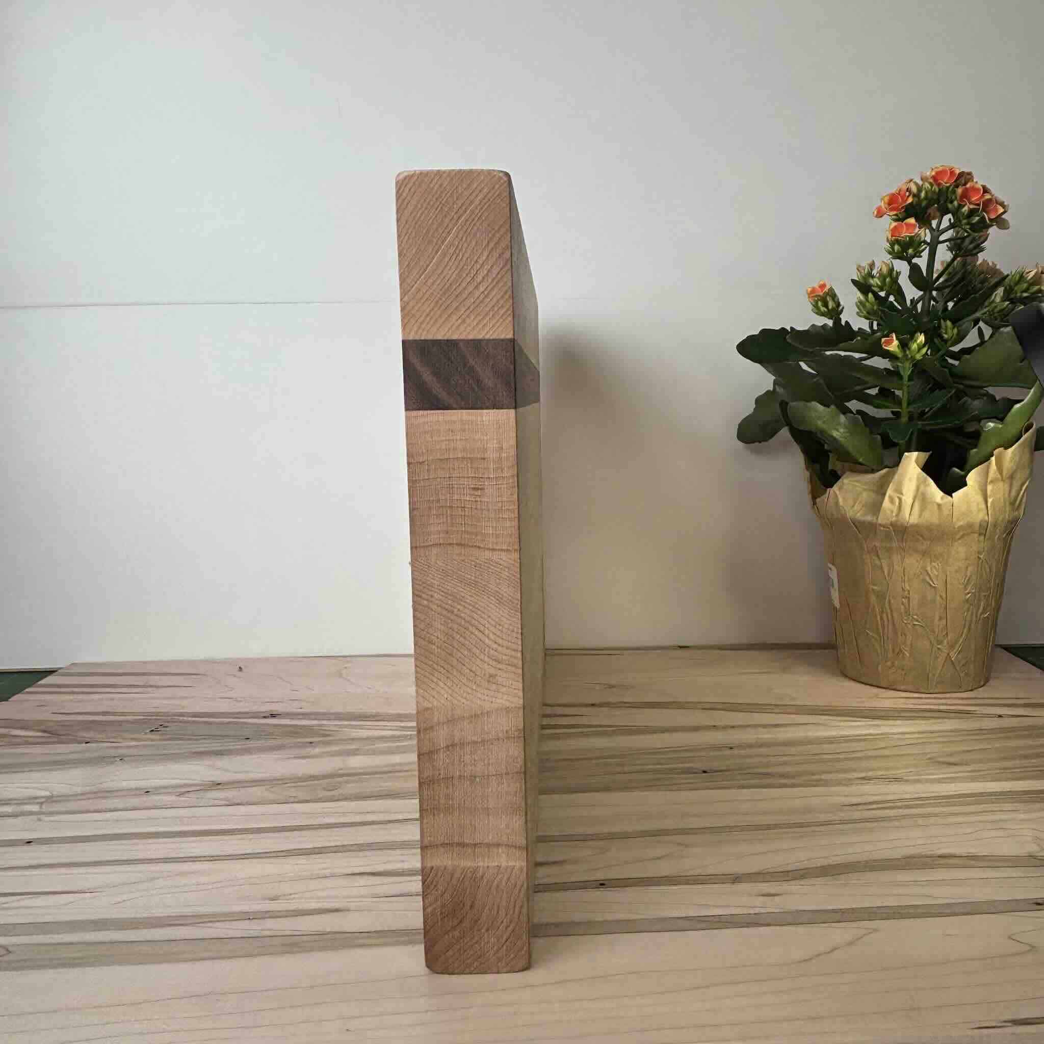 Wooden cutting board with potted orange kalanchoe flower on table