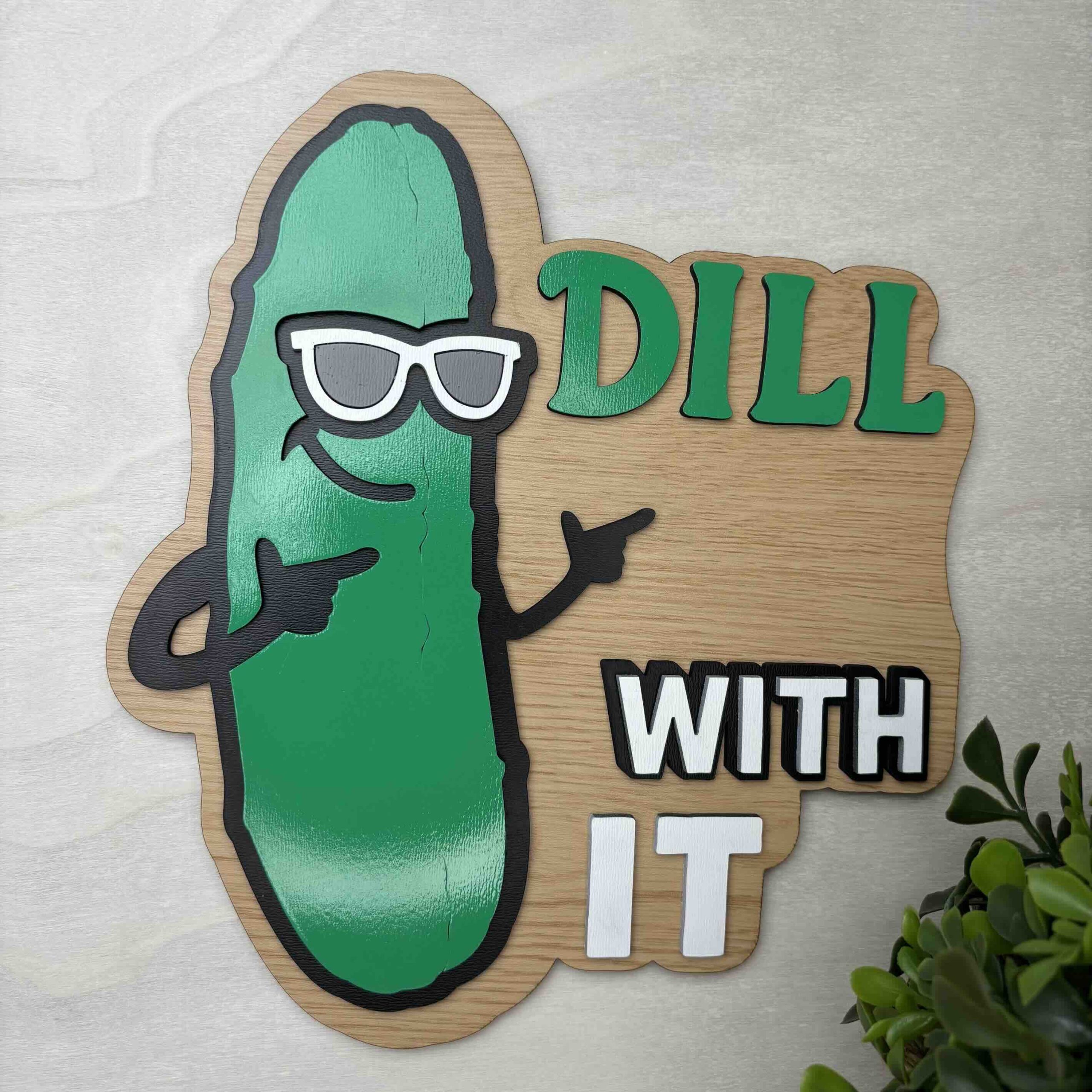 A playful wooden sign featuring a pickle with shades and the phrase 'Dill With It'