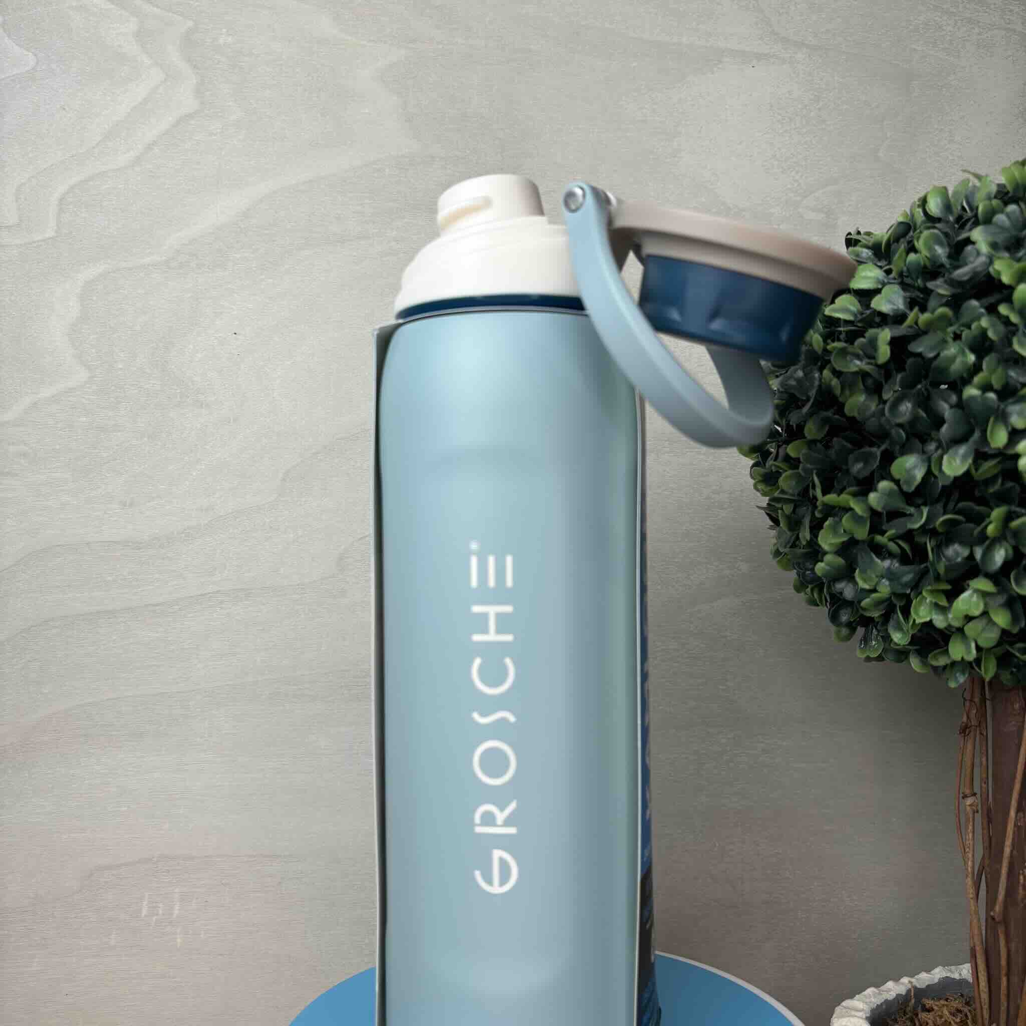 Blue Grosche insulated water bottle with secure lid on gray surface
